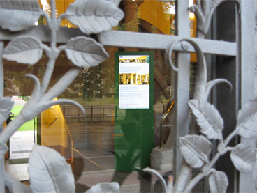 Die Infostele im Foyer des 
		Wissenschaftszentrums, durch das schmiedeeiserne Blattwerk der Tür fotografiert.